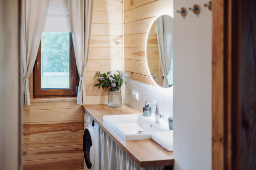 Przytulna łazienka, widok na podświetlane lustro z umywalką, obok okno